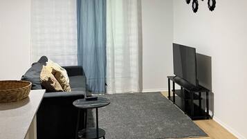 A living room with a ceiling fan, a sofa, a TV stand, a coffee table, and a wall-mounted TV.