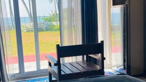 A room with a bench by a sliding glass door, a small table, and a cabinet. - Thodiyil 30 second away from beach couple private beach cabana (Paravur)