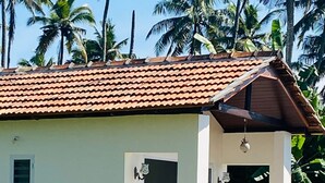 A small, single-story building with a tiled roof, a small porch with a bench, and a window. - Thodiyil 30 second away from beach couple private beach cabana (Paravur)