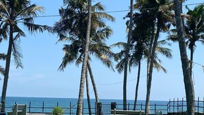 A coastal view with palm trees, a bench, and a fence. - Thodiyil 30 second away from beach couple private beach cabana (Paravur)