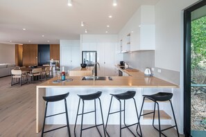 Een moderne keuken met een centraal eiland, barstoelen en een eethoek met stoelen.