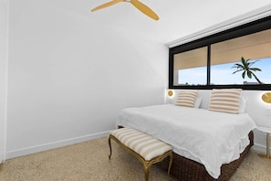 A bedroom with a bed, bedside tables, a bench, a ceiling fan, and a window with a view. - Breathtaking Ocean View Tamarama Beachfront (Tamarama)