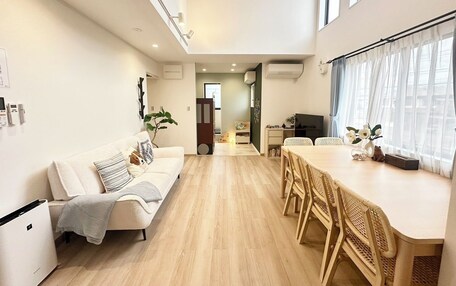 A modern living room with a sofa, dining table, chairs, and a TV.