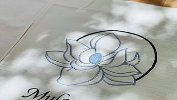 A white tote bag with a floral design and the text 'Mulan Stay' embroidered on it.