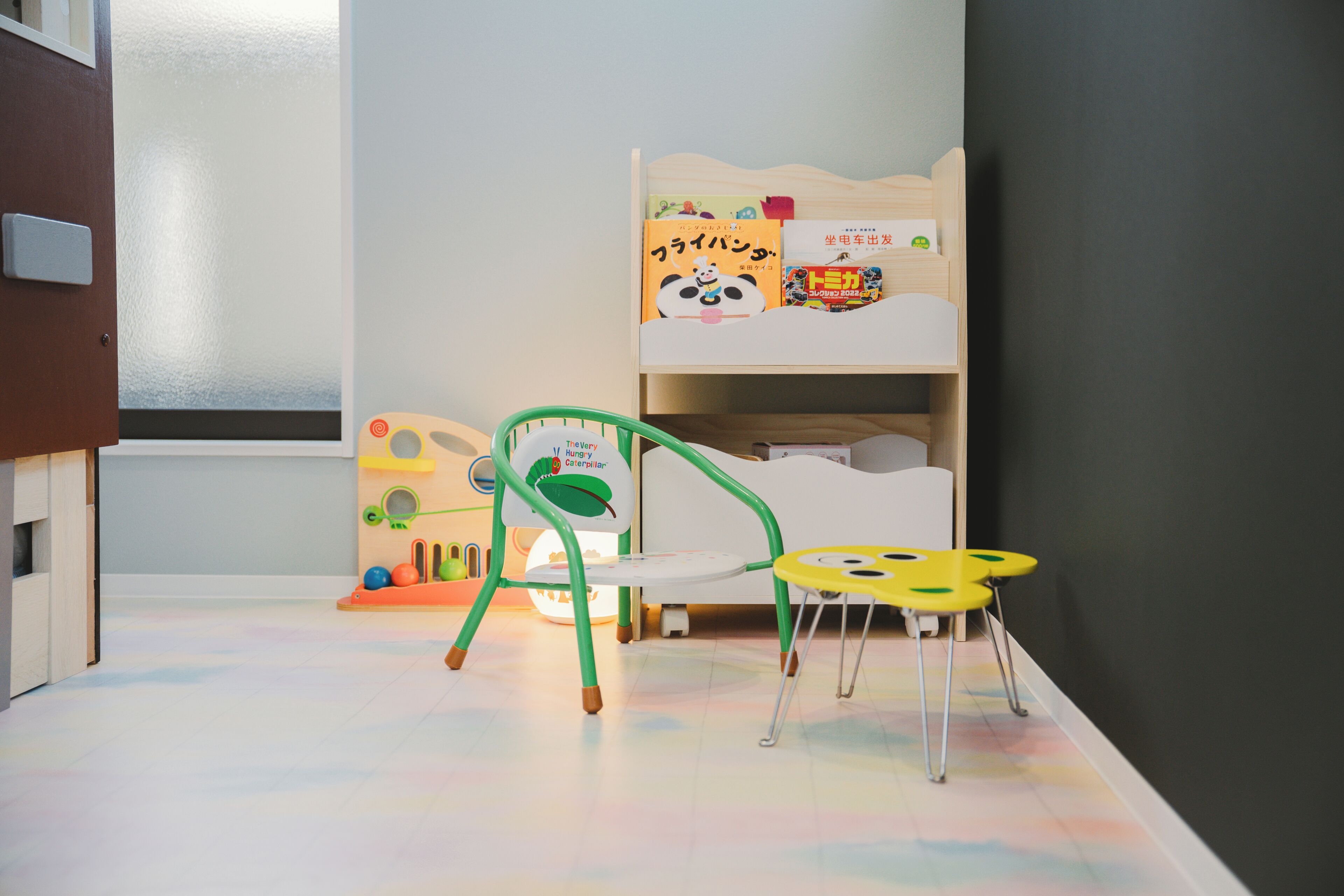 A child's room with bunk beds, a green chair, and a small table.