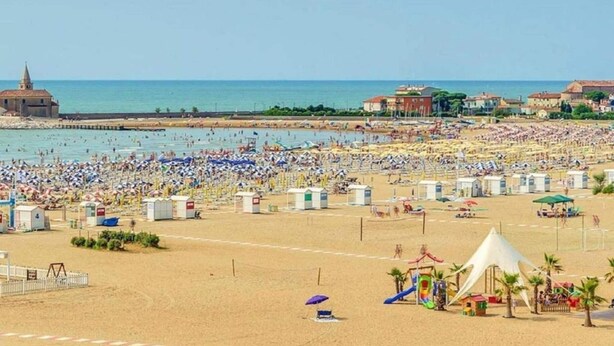 Una playa concurrida con numerosas sombrillas y gente.