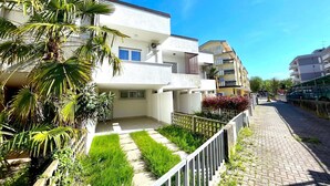 Un edificio residencial con balcones, un sendero pavimentado y abundante vegetación.