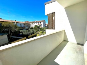 Ein Balkon mit Blick auf umliegende Gebäude und einen strahlend blauen Himmel.