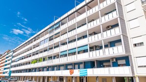 Ein mehrstöckiges Hotel mit Balkonen, einer blauen Markise und blauem Himmel.