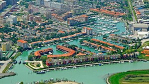 Luftaufnahme einer Marina mit zahlreichen vertäuten Booten, umgeben von Wohngebäuden und einer Brücke.