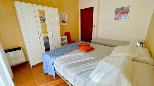 Ein Schlafzimmer mit einem Bett, einem Kleiderschrank, einem Schreibtisch und einem Stuhl.