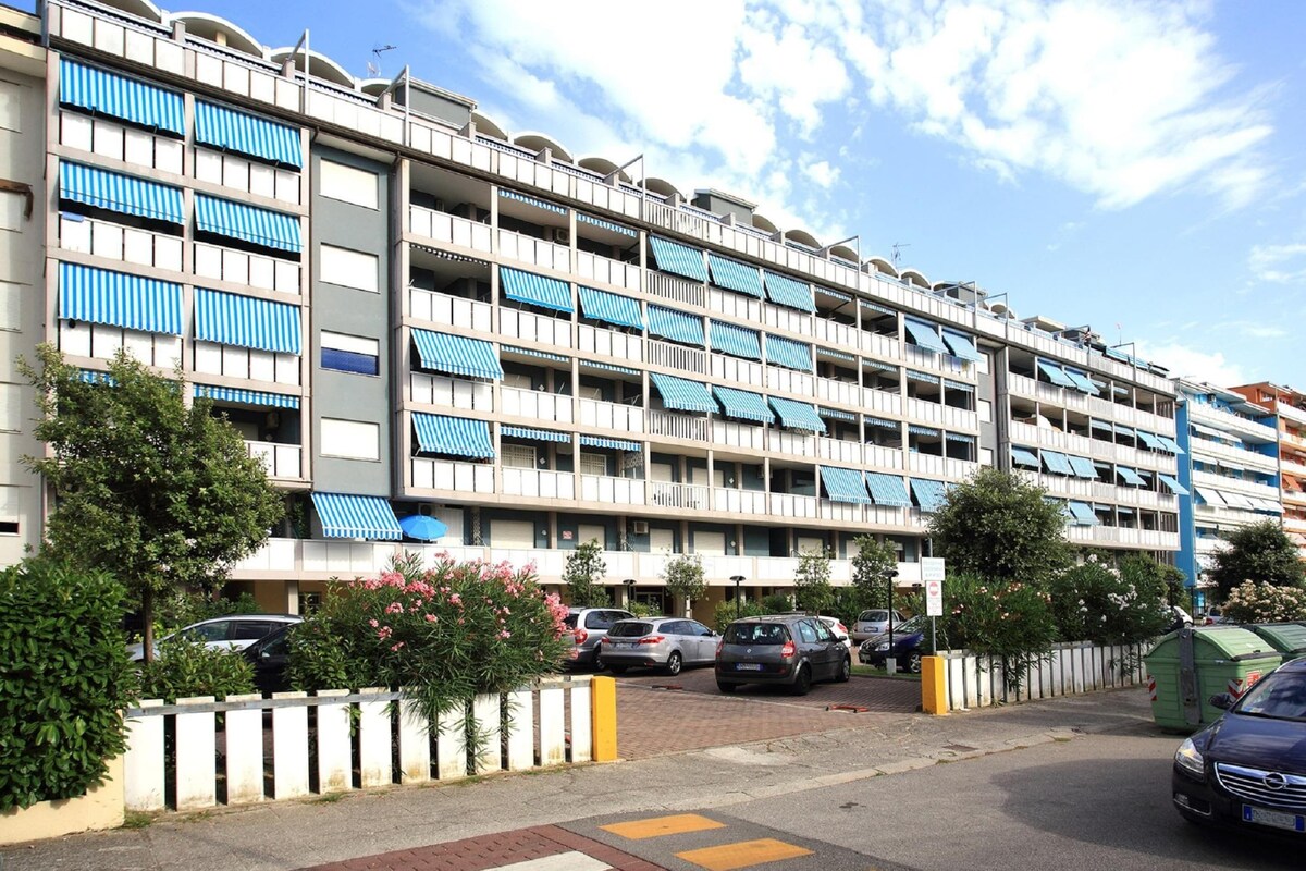 Ein mehrstöckiges Hotel mit Balkonen, einem Parkplatz und blauem Himmel.