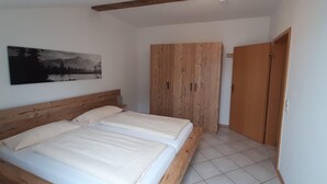 Un dormitorio con una cama de madera, un armario y un cuadro en la pared.