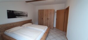 A bedroom with a wooden bed, a wardrobe, and a painting on the wall. - Beautiful Lodging in the Alps Near Bayrischzell (Bayrischzell)