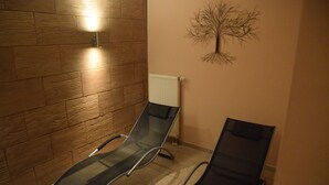 A room with two black lounge chairs, a wooden wall, a radiator, and a wall-mounted tree decoration. - Beautiful Lodging in the Alps Near Bayrischzell (Bayrischzell)