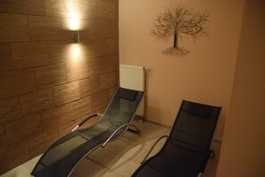 Una habitación con dos sillones reclinables negros, una pared de madera, un radiador y un adorno de árbol colgado en la pared.