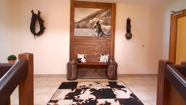 A hallway with a wooden bench, a cowhide rug, a framed picture, and a door. - Beautiful Lodging in the Alps Near Bayrischzell (Bayrischzell)