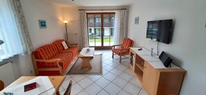 A living room with a sofa, armchair, coffee table, and television. - Beautiful Lodging in the Alps Near Bayrischzell (Bayrischzell)