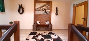A hallway with a wooden bench, a cowhide rug, a framed picture, and a door. - Beautiful Lodging in the Alps Near Bayrischzell (Bayrischzell)