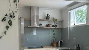 A modern kitchen with a built-in oven, dishwasher, and stainless steel sink. - Central & Cozy Raglan house - 10min walk to town! (Raglan)