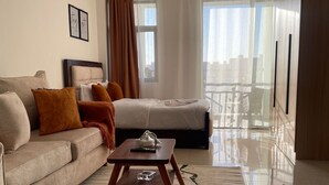 A modern hotel room with a sofa, a bed, a coffee table, and a view of the city. - Studio Apartment with a pool in Ruaka (Ruaka)