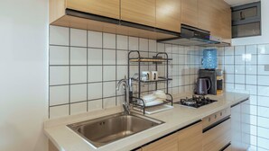 Eine Küche mit Spüle aus Edelstahl, Holzschränken, einem Gasherd und einer Kaffeemaschine.