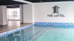 An indoor swimming pool with a tiled edge, a ceiling with a grid pattern, and a logo on the wall. - Studio Apartment with a pool in Ruaka (Ruaka)