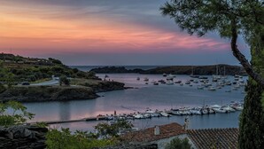 Vistes costaneres amb vaixells, un terreny rocos i un edifici de pedra.