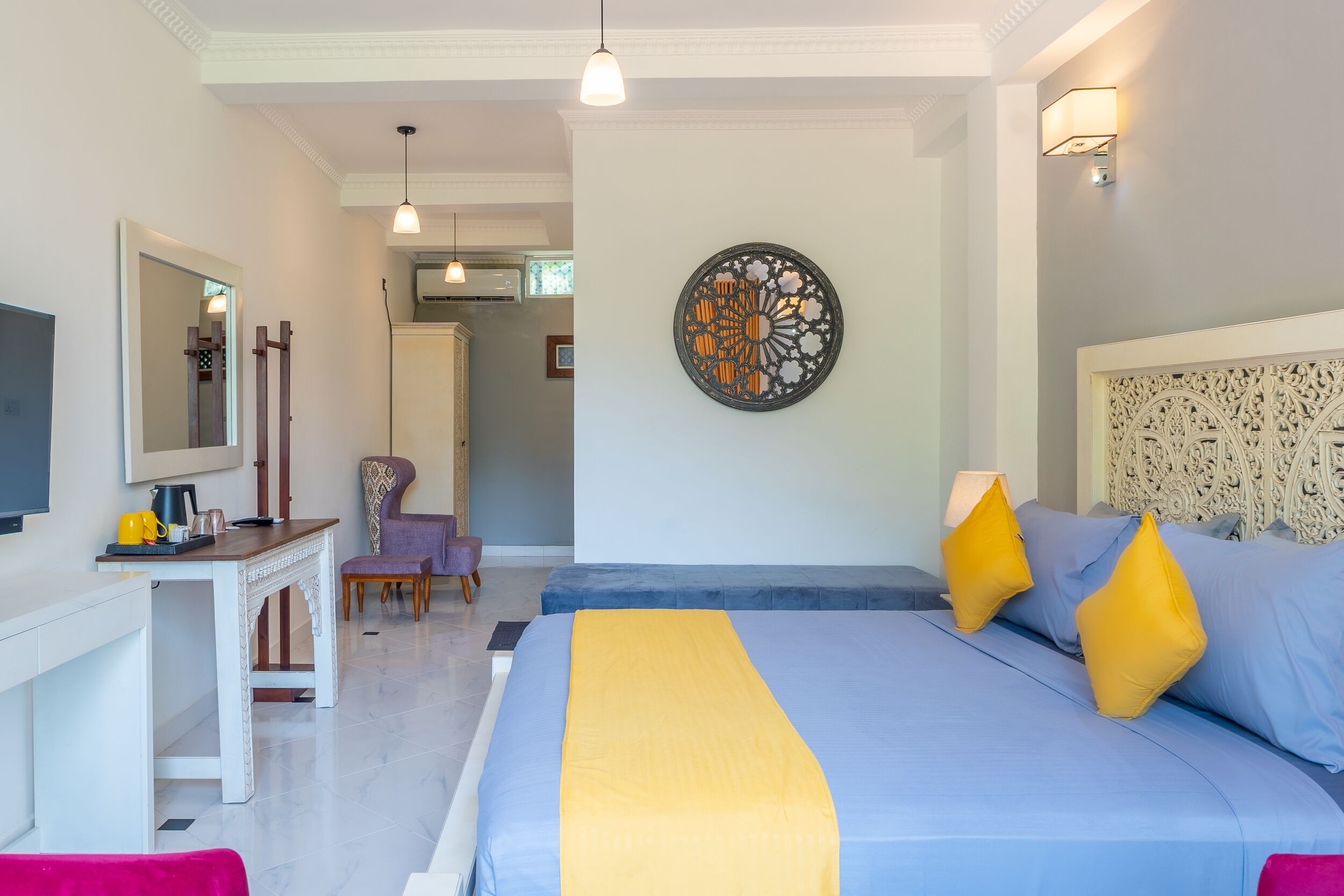 A bedroom with a bed, bedside table, chair, and artwork on the wall.