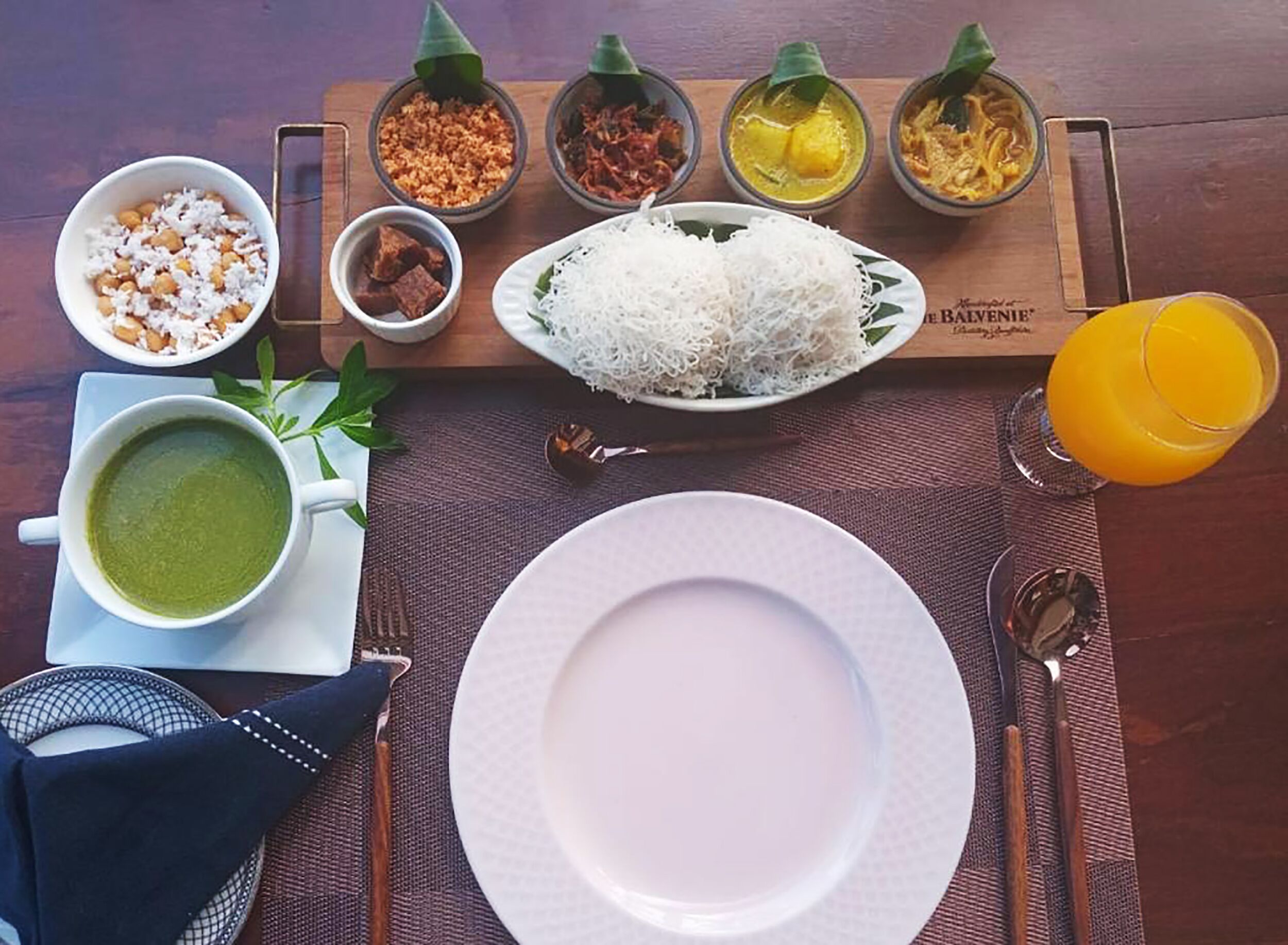 A meal setup with rice, soup, and various side dishes on a wooden table.