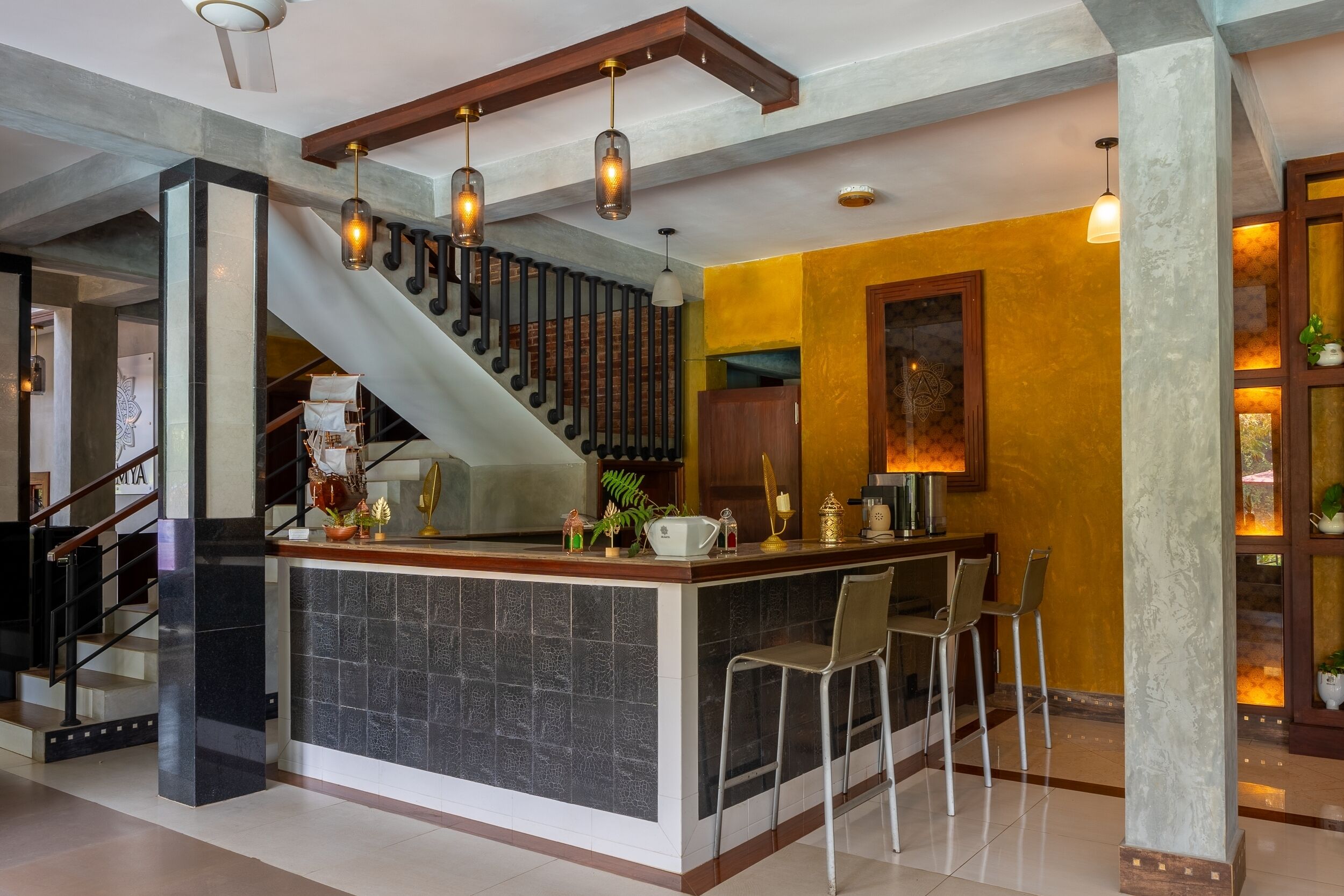 A kitchen with a central island, bar stools, a staircase, and a decorative wall.