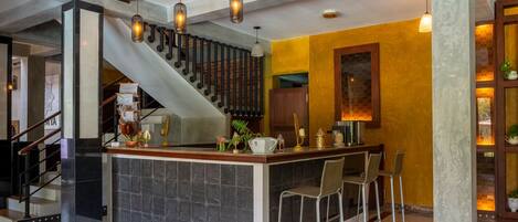 A kitchen with a central island, bar stools, a staircase, and a decorative wall.