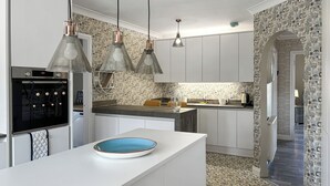 Cozinha moderna com ilha central, iluminação pendente e painel de azulejos padronizado.