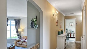 Um corredor com piso de madeira, um armário branco e uma porta que dá para outro quarto.
