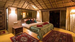 Une chambre à coucher avec un lit, une table de chevet, une grande fenêtre et un ventilateur de plafond.