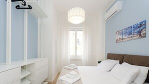 A bedroom with a bed, a dresser, a hanging light fixture, and a window. - VivimiHome - La Stella dei Navigli (Milan)