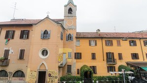 A building with a bell tower, arched windows, and a door with graffiti. - VivimiHome - La Stella dei Navigli (Milan)