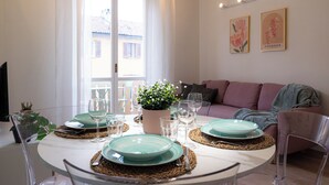 A dining area with a round table set for four, a potted plant, and two framed pictures on the wall. - VivimiHome - La Stella dei Navigli (Milan)