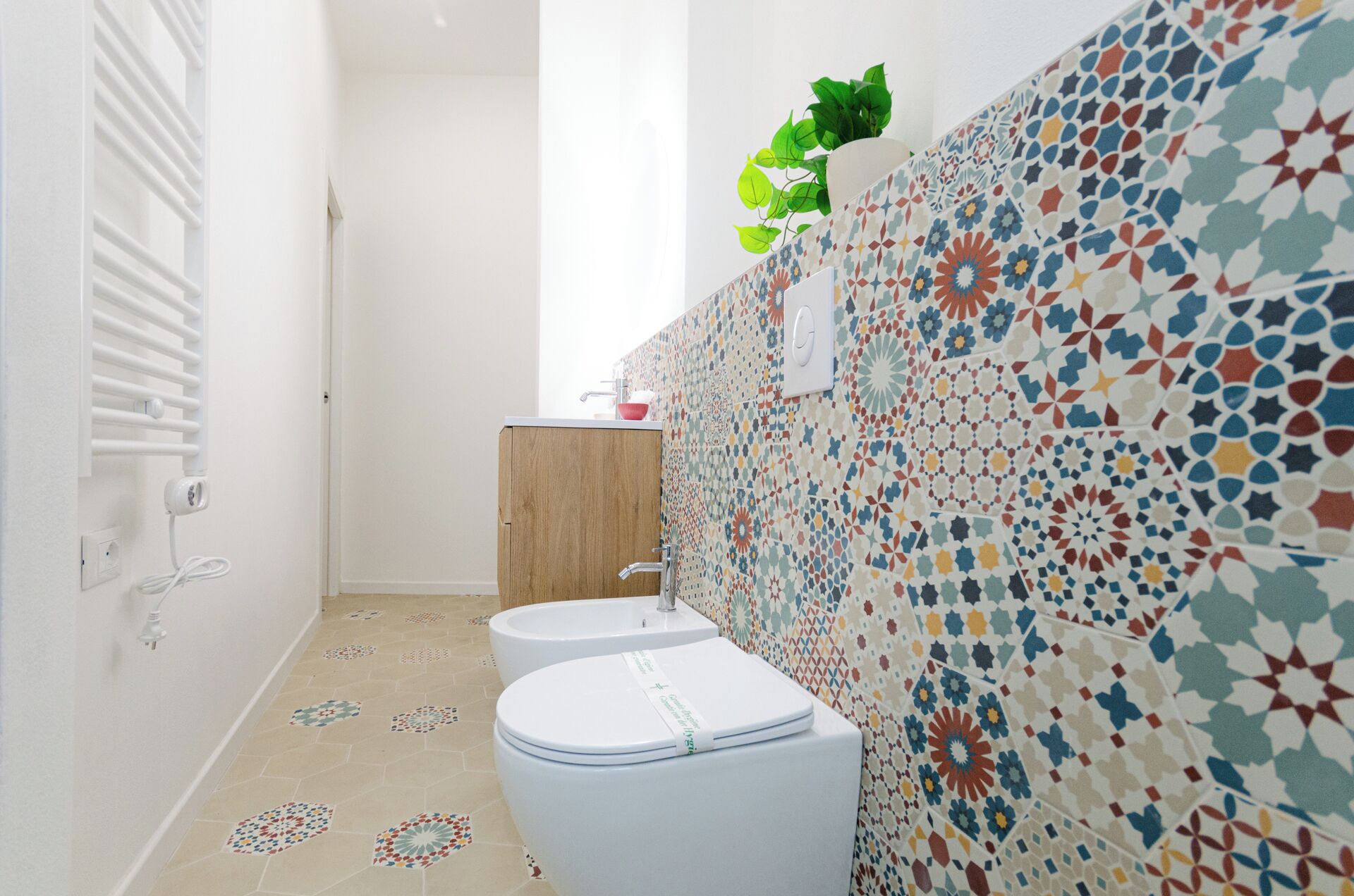 Een badkamer met een toilet, wastafel en betegelde wanden.