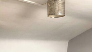 Een slaapkamer met een bed, nachtkastje, lamp en hangende verlichtingsarmatuur.