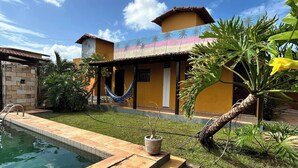 A residential property with a swimming pool, a hammock, and a well-maintained garden. - Beautiful and cozy room in Casa 7 Mares (Rio Grande do Norte city)