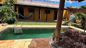 A pool with a ladder, a hammock, and a house with a colorful mural. - Beautiful and cozy room in Casa 7 Mares (Rio Grande do Norte city)
