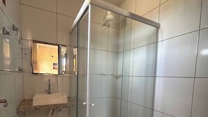 A bathroom with a glass shower enclosure, a sink with a mirror, and a toilet. - Nice and cozy room with pool (São Miguel do Gostoso)