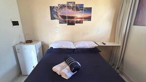 A hotel room with a bed, a wall-mounted artwork, a small table, and a heater. - Nice and cozy room with pool (São Miguel do Gostoso)