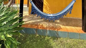 A yellow building with a tiled roof, a hammock, and a door labeled 'X4pa'. - Nice and cozy room with pool (São Miguel do Gostoso)