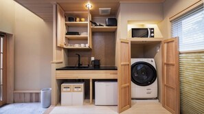Eine kompakte Küche mit Spüle, Mikrowelle und Waschmaschine, Holzschränken und einem kleinen Kühlschrank.