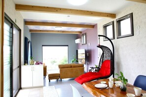 A modern interior with a dining area, sofa, and a hanging chair. - Just a short walk to the beach Newly built ocean / Kunigami County Okinawa (Kunigami County)