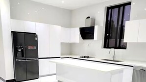 Una cocina moderna con armarios blancos, un refrigerador negro, una isla integrada y una ventana.