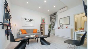 Una sala de estar moderna con un sofá, dos sillas negras, una mesa de centro y una estantería.