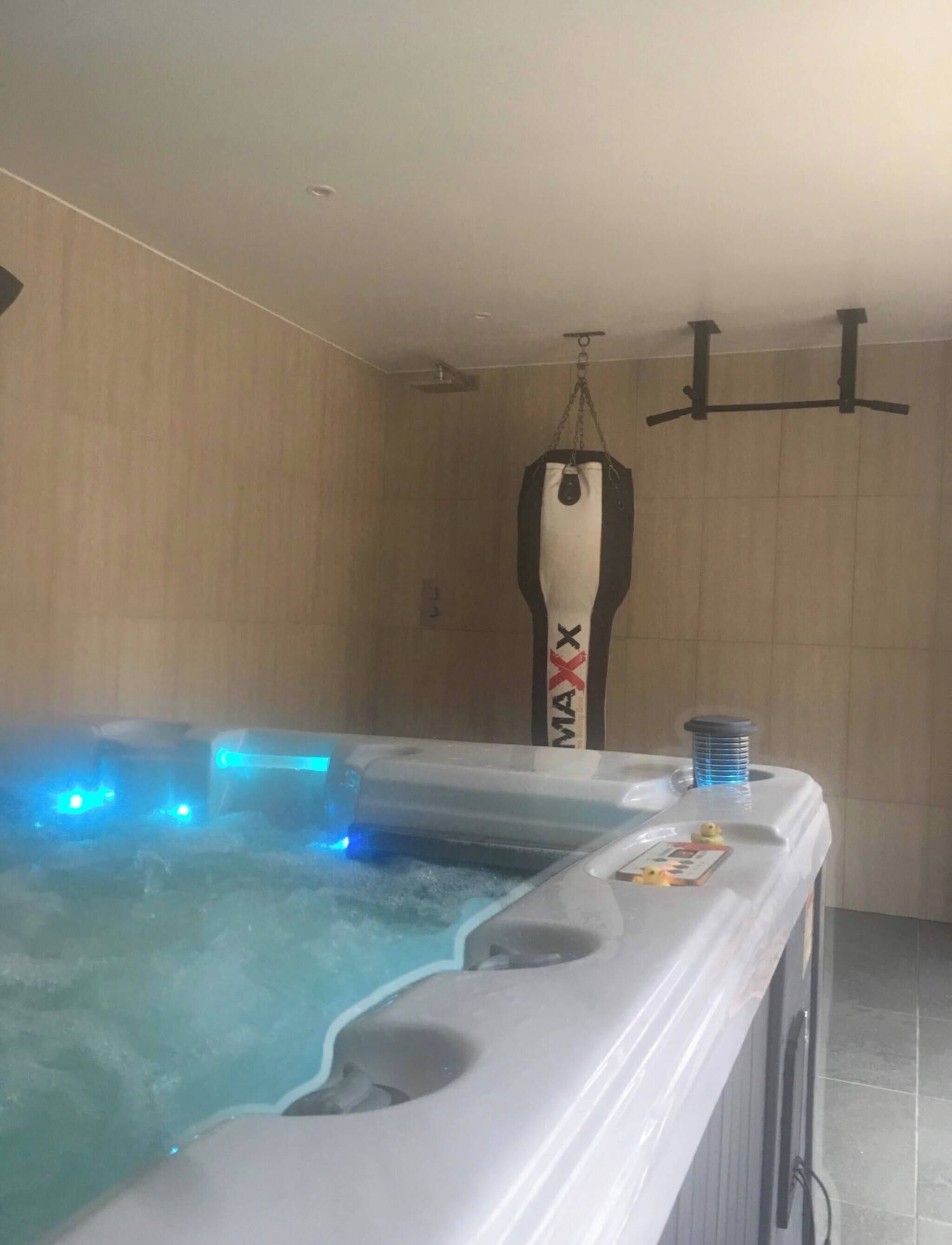 Un jacuzzi con un saco de boxeo colgante, un patito de goma y un perchero.